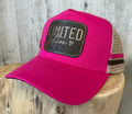Hot pink trucker cap with dark leather Limited Edition patch on a wooden display